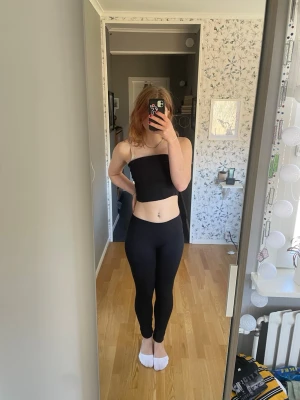 Svarta basic leggings - Säljer ett par svarta, tighta leggings med hög midja. De är stretchiga och sitter skönt mot kroppen, perfekta till både oversized tröjor och crop tops. Materialet känns mjukt och följsamt, troligen bomull eller bomullsblandning. Inga synliga detaljer eller loggor.