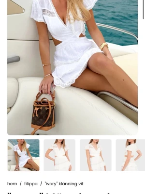 Vit omlottklänning med spetsdetaljer - Söt vit kortklänning från Filippa med omlottmodell, spetsdetaljer och volangkant. Klänningen har v-ringning, korta ärmar och öppna partier i midjan. Perfekt för sommarens alla tillfällen.