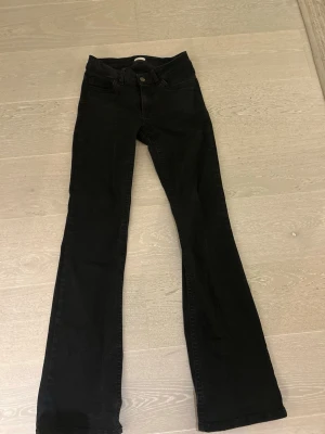 Svarta bootcut jeans från Molly - Snygga svarta bootcut jeans från Nelly med klassisk femficksdesign och knappgylf. Jeansen har en något utsvängd passform nertill och är tillverkade i ett stretchigt denimtyg som sitter bekvämt. Perfekta för en trendig och avslappnad look.