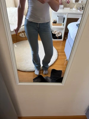Ljusblå utsvänga jeans - Säljer ett par ljusblå jeans med utsvängd passform och klassisk femficksdesign. Jeansen har normalhög midja och är tillverkade i ett mjukt denimtyg som sitter snyggt på kroppen. Perfekta för en avslappnad och stilren look.