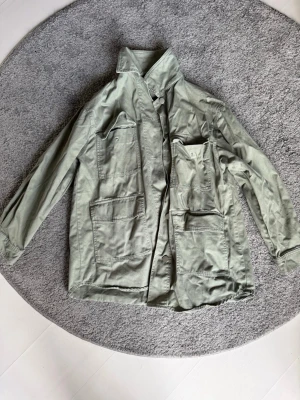 Grön overshirt från Zara - Snygg ljusgrön overshirt från Zara med fyra stora fickor framtill och klassisk krage. Overshirten är tillverkad i ett mjukt bomullstyg och har en avslappnad passform. Perfekt att slänga över en hoodie eller t-shirt för en cool lager-på-lager-look.