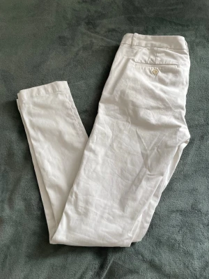 Vita chinos från Polo Ralph Lauren - Snygga vita chinos från Polo Ralph Lauren med klassisk passform. Byxorna har bakficka med knapp och Polo-logga, samt hällor för bälte. Perfekta för en stilren och fräsch look. Materialet känns mjukt och bekvämt. Skriv för frågor eller bilder! 100cm långa.