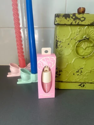 BUBS rosa läppolja by H&M - Snyggt rosa läppolja - BUBS by H&M. Kommer i en rosa kartong med texten 'BUBS'. Perfekt för att ge läpparna fukt och glans med en trendig look.