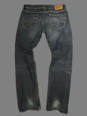 Straight/bootcut jeans från diesel - Säljer ett par klassiska blå jeans från Diesel, modell Larkee. Jeansen har raka ben, snygga slitningar och två bakfickor med dekorativa sömmar. Perfekt för dig som gillar en avslappnad och tidlös stil.