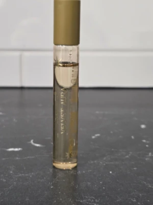 Rituals Velvet Aura parfym - Rituals Velvet Aura parfym i en smal, cylindrisk glasflaska med guldfärgat lock. Flaskan är transparent med guldiga detaljer och text. Perfekt att ha med sig i väskan för att alltid kunna fräscha upp sig med en lyxig doft.