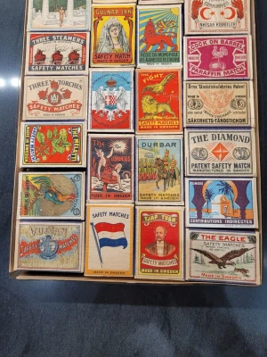 Samling tändsticksaskar vintage motiv - Unik samling med 84 tändsticksaskar från olika märken, alla med färgglada och detaljerade vintage-motiv. Askarna har illustrationer av djur, flaggor, personer och exotiska platser. De flesta är tillverkade i Sverige och har klassiska etiketter i papper.