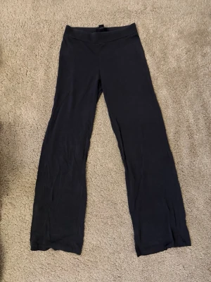 Mörkgråa Lågmidjade mjukisbyxor från Monki XS - Mörkgråa Lågmidjade mjukisbyxor från Monki i storlek XS. Byxorna har raka och vida ben, bred resår i midjan och är gjorda i ett mjukt, väldigt tunt och stretchigt material. .