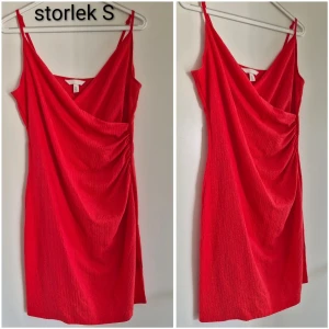 Röd omlottklänning med drapering - Snygg röd kortklänning med omlott och draperad framsida. Klänningen har smala axelband och en djup v-ringning, vilket ger en trendig och ungdomlig look. Perfekt för dig som vill sticka ut med färg och stil.