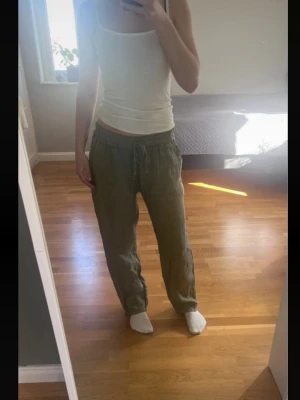 Gröna linnebyxor med raka ben - Snygga gröna linnebyxor med avslappnad passform och resår i midjan. Byxorna har raka ben och är perfekta för en chill och stilren look. Materialet är luftigt linne som passar bra till varma dagar.