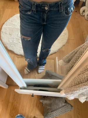 Blå slitna bootcut jeans Från gina - Säljer ett par blå bootcut jeans med slitningar på knäna och låret. Jeansen har klassisk femficksdesign, normalhög midja och dragkedja med knapp. Perfekta för en avslappnad och trendig look. ⚠️ ‼️ STORLEK 170 ‼️⚠️