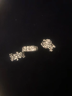 Tre silverringar med detaljerad design - Säljer tre coola silverringar med unika mönster och detaljer. En ring har blommönster, en har snirkliga ornament och den tredje har en stiliserad blomform. Perfekt för dig som gillar att mixa och matcha accessoarer med personlig touch.