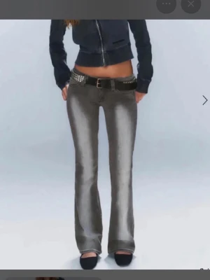 Grå raka jeans med tvättad look - Säljer ett par grå bootcut jeans och snyggt tvättad effekt på benen. Jeansen har klassisk femficksdesign och är tillverkade i denim. Perfekta för dig som gillar en avslappnad och trendig stil. Lite uppsydda