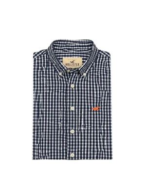 Rutig skjorta från Hollister  - Snygg rutig skjorta från Hollister i mörkblått och vitt. Klassisk button-down krage, vita knappar och en liten orange logga broderad på bröstet. Tillverkad i mjuk bomull, perfekt för en avslappnad men stilren look. Riktigt fet skojorta nu till sommaren, L i skjortan sitter som S
