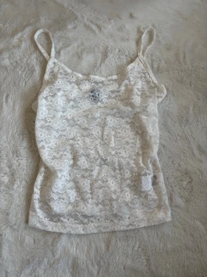 Vit spetslinne från SHEIN - Snyggt vitt spetslinne från SHEIN i storlek XS. Linnet har tunna axelband och är helt täckt av blommig spets, vilket ger en romantisk och trendig look. Perfekt att styla med jeans eller kjol för en fräsch outfit. Använt få gånger, pris kan diskuteras. 
