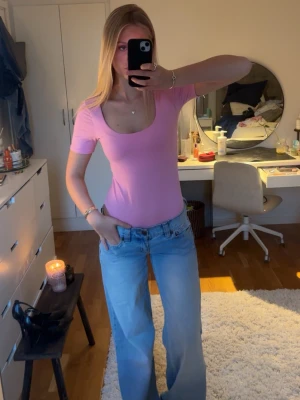 Rosa body  - Snygg body perfekt till fest eller vardag! Modellen har en djup, rundad ringning och sitter tight mot kroppen. Perfekt att styla med jeans eller kjol för en trendig look.