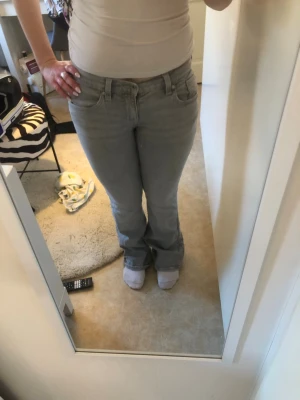 Ljusgrå bootcut jeans med broderi - Säljer ett par ljusgrå bootcut jeans med snygga broderade detaljer på bakfickorna, dem är lågmidjade och använda fåtal gånger! Jag är 162 som referens, skriv för mått och om ni har frågor!