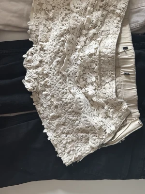 Beige spetsiga shorts med dragkedja - Snygga beige shorts med vacker spets och blommiga detaljer. De har en dragkedja i sidan och är perfekta för en somrig look. Passar dig som gillar romantisk och feminin stil.