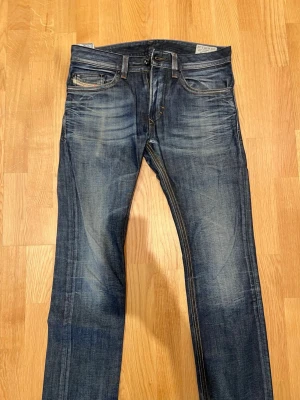 Diesel jeans - Snygga mörkblå jeans från diesel med klassisk femficksdesign och diskreta slitningar framtill. Jeansen har raka ben och är tillverkade i denim med tydliga kontrastsömmar. Perfekta för en avslappnad och trendig look.