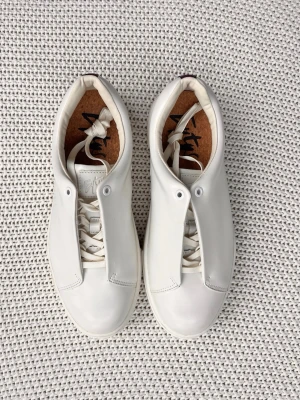 Vita sneakers från Eytys  - Stilrena vita sneakers från Eytys i slätt läder med minimalistisk design. Skorna har vita snören, diskret logga på innersulan och en unik plös som täcker snörningen. Perfekta för dig som gillar clean och modern stil.