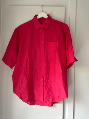 Rosa kortärmad skjorta från Gant - Snygg rosa skjorta från Gant med korta ärmar och klassisk krage. Skjortan har knappar framtill och en bröstficka. Perfekt för dig som vill ha en färgstark och bekväm skjorta i garderoben. Stor i storleken.