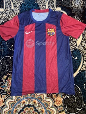 FC Barcelona matchtröja Nike - Säljer en FC Barcelona matchtröja från Nike med klassiska blå och röda vertikala ränder. Tröjan har klubbmärket, Nike-logga och Spotify som sponsortryck på bröstet. Tillverkad i lätt och ventilerande material, perfekt för fotbollsträning eller match.