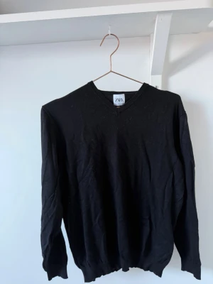 Svart V-ringad stickad tröja Zara - Klassisk svart stickad tröja från Zara med V-ringning, perfekt basplagg i garderoben och enkel att matcha. Materialet känns mjukt och lätt.