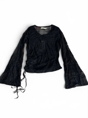 Svart mesh topp med vida ärmar - Svart mesh topp från ICHI med vida långa ärmar och snörningsdetalj i sidan. Toppen har ett broderat mönster framtill och är lätt transparent. Storlek L men skulle säga att den passar som M/S.