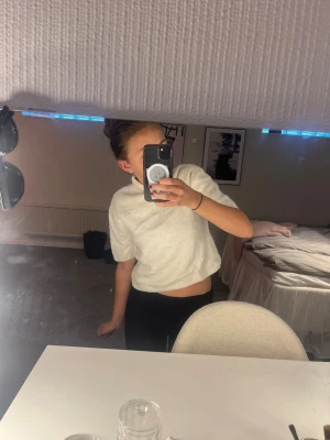 Vit kortärmad polotröja - Säljer en vit, mjuk och kortärmad polotröja med lös passform. Tröjan har en hög krage och är något croppad, vilket ger en modern look. Perfekt att styla med både jeans och kjol för en trendig outfit. Säljer pågrund av för liten storlek, (jag har xs)