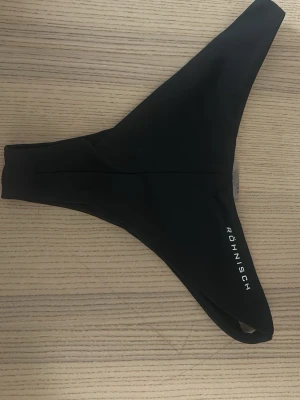 Svart bikiniunderdel från Röhnisch - Svart bikiniunderdel från Röhnisch med enkel och stilren design. Modellen har en klassisk passform och är tillverkad i ett mjukt och stretchigt material som passar perfekt för strand och bad.