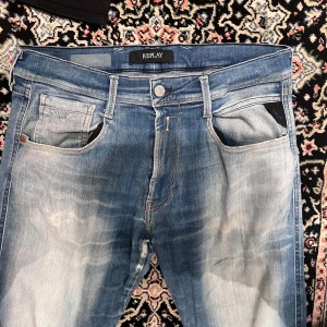 Replay anbass 32/34 sjukt snygg tvätt - Snygga ljusblå jeans från Replay med klassisk femficksdesign och diskret slitning framtill och baktill. Jeansen har raka ben och normal passform, med detaljerade sömmar på bakfickorna och Replay-logga på bakre läderpatch. Perfekta för en avslappnad stil.