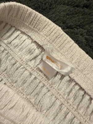 Vit långkjol från Gina Tricot - Säljer en vit långkjol från Gina Tricot med bred resår i midjan och volangdetaljer. Kjolen har en luftig och flowy passform, perfekt för varma dagar. Materialet känns mjukt och bekvämt mot huden. Perfekt för nu under sommaren! 