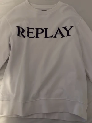 Vit sweatshirt från Replay - Använt den ett par gånger. Säljer en vit sweatshirt från Replay med stort svart tryck på bröstet. Tröjan har rund halsringning och långa ärmar. Materialet är mjukt och bekvämt, perfekt för en avslappnad look. Ingen huva, klassisk passform.