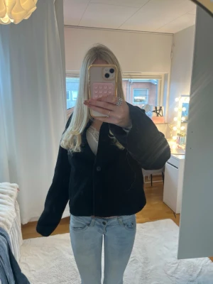 Svart kavajjacka i manchester - Säljer en svart kavajjacka i manchester med klassisk krage och knäppning framtill. Jackan har en loose passform och långa ärmar, perfekt att slänga över en outfit för en cool och enkel look.