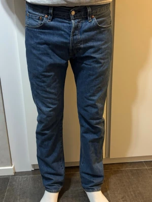 Levi's blå raka jeans - Klassiska blå jeans från Levi's i rak modell med fem fickor och knappgylf. Jeansen har en blå tvätt och är tillverkade i slitstark denim. Perfekta för en avslappnad och tidlös stil.