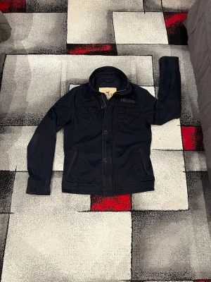 Hollister Jacka  - Riktigt snygg svart jacka från Hollister med klassisk krage|två bröstfickor med lock och knappar framtill|Storlek M| färg=Navy| Hör bara av dig om du har några frågor!⛳️🍾