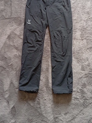 Svarta täckbyxor från Haglöfs - Säljer ett par svarta täckbyxor från Haglöfs med raka ben och dragkedjeförsedda fickor framtill. Byxorna har diskret logga på vänster lår och är tillverkade i slitstarkt material som passar perfekt för kalla dagar utomhus. Hör av dig vid frågor 