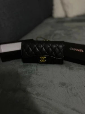  handväska - Säljer en svart quiltad handväska med klassiskt guldigt CC-spänne framtill. Väskan har kedjerem i guld och svart läder, samt elegant rektangulär form. Perfekt för dig som gillar lyxiga accessoarer och tidlös design.