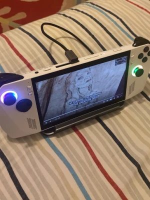 Vit rog ally handhållen spelkonsol - Säljer en vit rog ally handhållen spelkonsol med RGB-belysta styrspakar, stora ventiler och flera portar. Konsolen har en bred skärm och klassiska knappar, perfekt för gaming på språng. Materialet är plast och designen är modern och stilren.