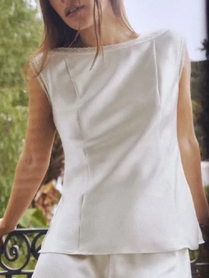 Vit ärmlös linnetopp - Snygg vit linnetopp med enkel och clean design. Toppen är ärmlös och har en rak passform med diskret båtringad hals. Perfekt för varma dagar och enkel att styla med olika accessoarer.