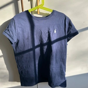Marinblå t-shirt från Ralph Lauren - Aldrig använd. Nypris 700 kr  Klassisk marinblå t-shirt från Ralph Lauren med korta ärmar och rund hals. T-shirten har den ikoniska vita Polo-loggan broderad på bröstet. Tillverkad i mjuk bomull.