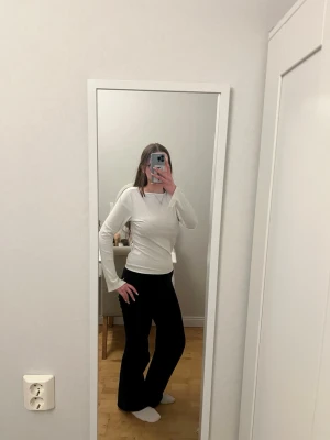 Vit ribbad långärmad topp - Säljer en enkel och stilren vit långärmad topp med ribbad struktur. Toppen har en rund halsringning och är i ett mjukt, stretchigt material som sitter snyggt på kroppen. Perfekt att matcha med jeans eller kjol.