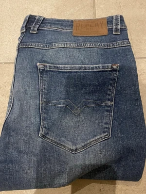 Blå jeans från Replay - Snygga blå jeans från Replay med klassisk femficksdesign och diskret slitning. Jeansen har raka ben och en läderpatch med Replay-logga bak i midjan. Materialet är mjukt denim i bomull med en cool tvättad look.