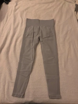 Grå sömlösa leggings med hög midja - Snygga grå leggings med hög midja och sömlös design. De har ribbade detaljer längs sidorna och är tillverkade i ett stretchigt material som passar perfekt för träning eller chill. Tight passform som framhäver benen.