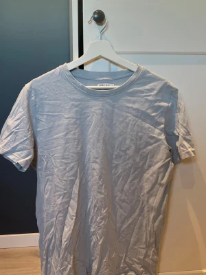 Ljusgrå basic t-shirt från studio total  - En enkel och stilren ljusgrå t-shirt från Weekday. Klassisk rund halsringning och korta ärmar. Perfekt basplagg i mjuk bomull som passar till allt. Snygg att bära både ensam eller under en skjorta.