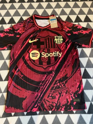 Barcelona Nike matchtröja röd/svart M - Säljer en Barcelona matchtröja från Nike i röd och svart med grafiskt mönster. Tröjan har klubbmärke, Nike-logga och Spotify som sponsor på bröstet. Tillverkad i lätt och ventilerande material, perfekt för fotboll eller träning.