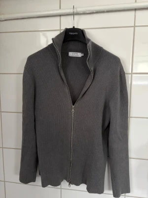 Grå ziptröja från LUNG - Full zip från ljung som bäst jag vet inte finns i sortimentet längre. Den är tjock och funkar som cardigan såväl som kofta. Den grå färgern med den silvriga dragkedjan ger en stilren look som sällan går fel. Storlek M