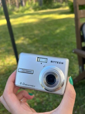 Nytech digitalkamera 8.0 MP - Snygg silverfärgad digitalkamera från Nytech med 8.0 megapixlar och 3x optisk zoom. Kameran har en kompakt rektangulär design, inbyggd blixt och stor display på baksidan. Perfekt för dig som vill ta enkla bilder och ha en smidig kamera i fickan. Batteridriven, batterier medföljer, SD/minneskort medföljer EJ.  