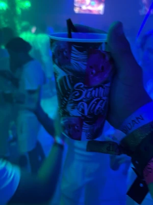 Färgglad plastmugg från solsidan i Ayia napa - Säljer en plastmugg med färgglatt tryck och texten 'Saint Vibes'. Muggen har motiv av vattenmelon och palmer, samt svart sugrör. Perfekt för festival eller fest och rymmer en generös mängd dryck.