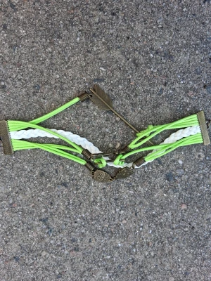 Flätat armband med ugglor och pil - Snyggt armband med limegröna och vita flätade band, dekorerat med metallberlocker i form av ugglor, pil och texten 'love'. Armbandet har flera lager och coola detaljer i antikguldfärgad metall. Perfekt för dig som gillar unika accessoarer och vill sticka ut.