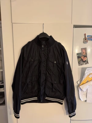 Moncler field jacket  - En moncler field jacket med sjysta fickor över hela framsidan av jackan och den är tun och skön till sommaren. Den har dock ingen dragkedja och en knap är sönder därav priset 